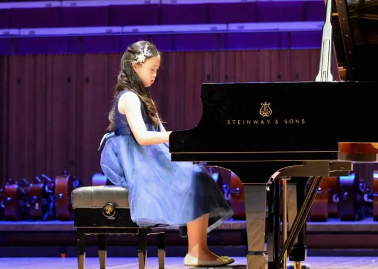 A student performing on a Steinway grand at recital