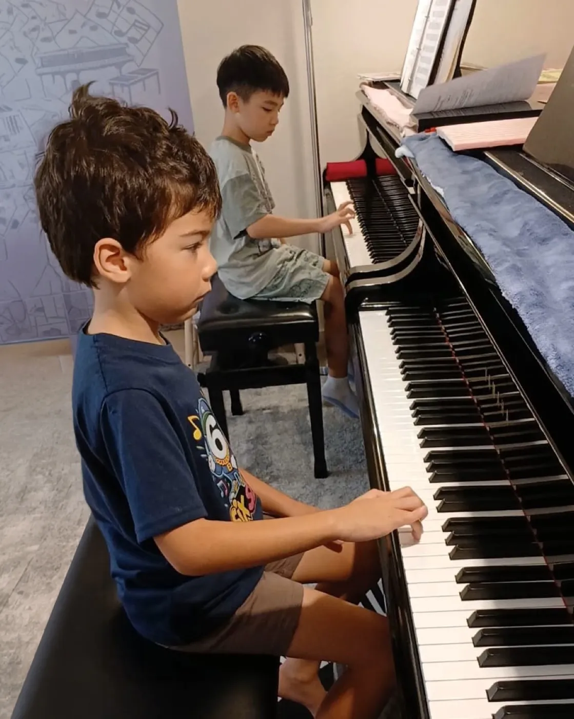Two young students at the piano during a lesson